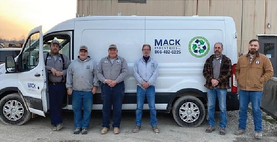 Mack Industries team members standing in front of one of their service trucks